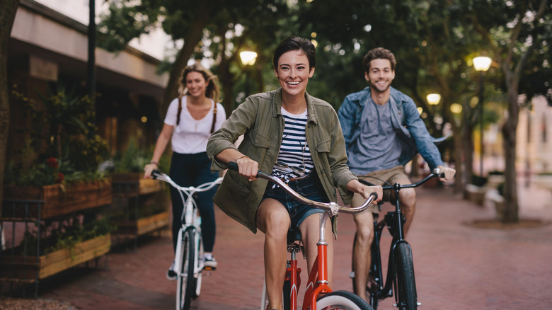 Three young people cycling down the street