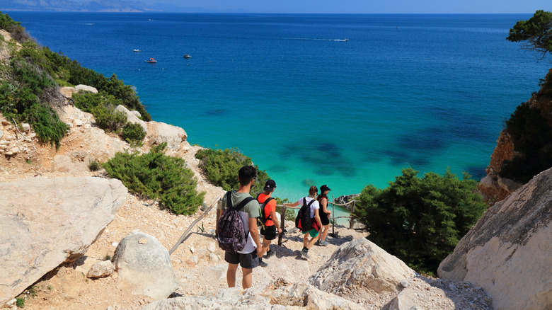 Hikers walking down the rocky path to Cala Goloritze