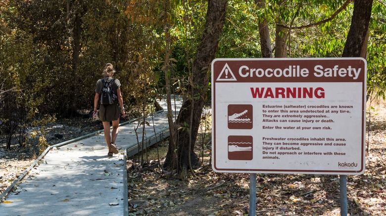 woman hiking past crocodile safety sign