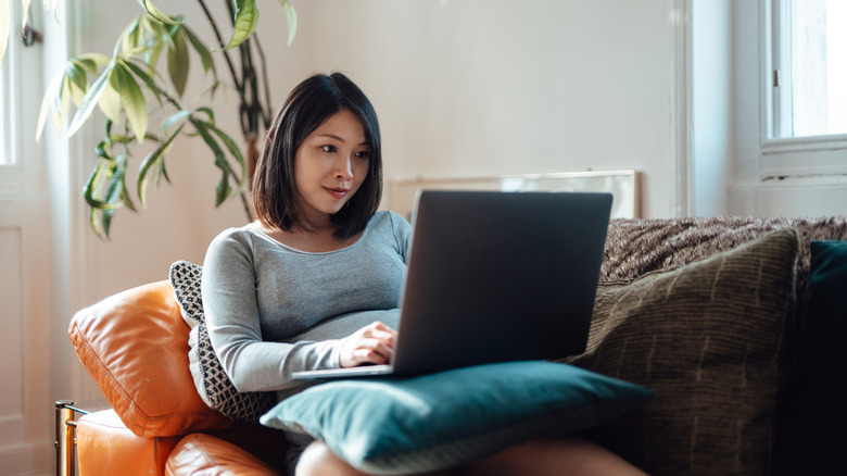 Woman working on computer from couch