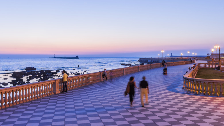 Black and white tile terrace at the Livorno seafront with pedestrians walking at sunset