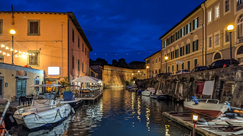 Boats moored along an Italian canal with lights hung along the buildings