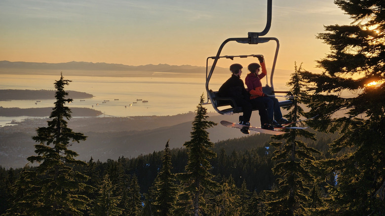 Snowboarder and skier on a chairlift at sunset on Mt. Seymour in Vancouver