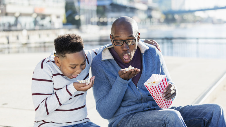 Boy and man eating popcorn in city setting