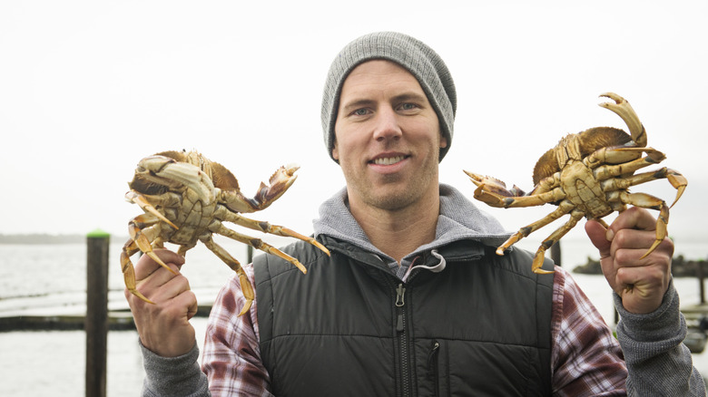 Man on Oregon coast holding two freshly caught crabs