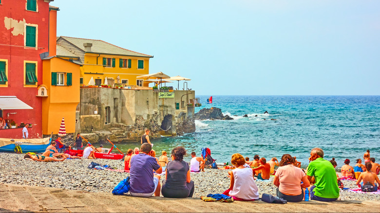 People sitting on the beach in Boccadasse, a village in Genoa, Italy