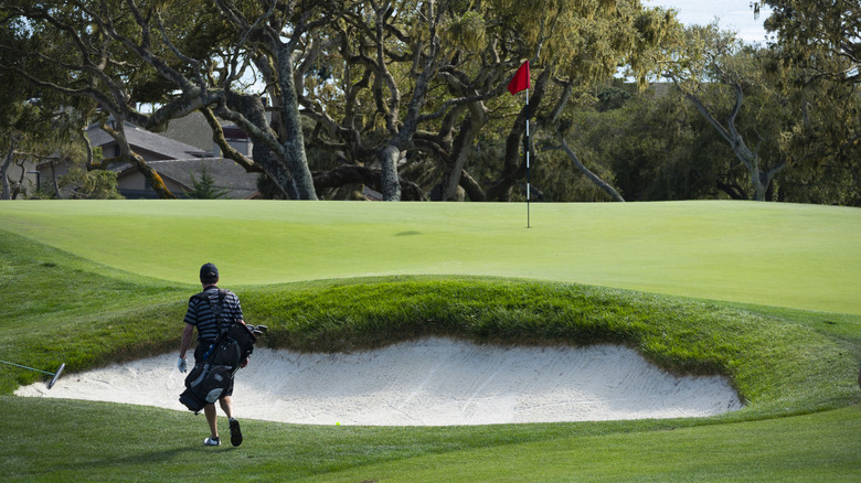 Golfer walking past sixth green at The Hay golf course at Pebble Beach