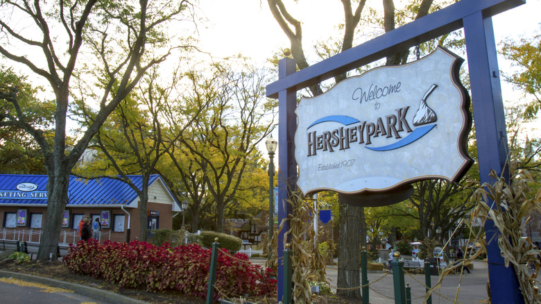 Blue welcome sign to Hersheypark with trees in the background