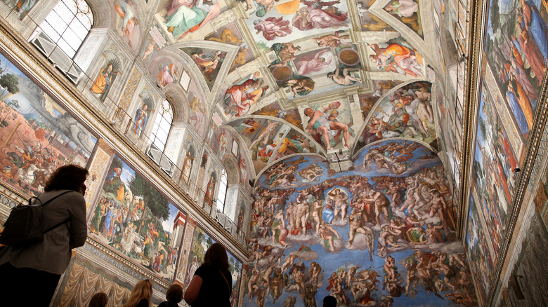 Visitors to the Sistine Chapel look at the vaulted ceiling