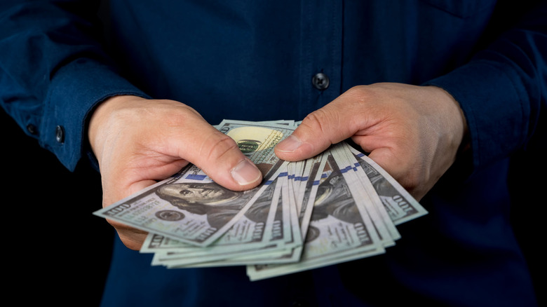 A person holding a stack of $100 bills