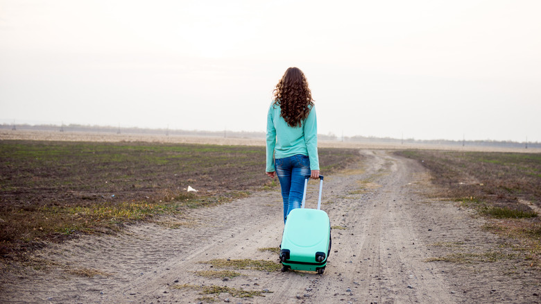 Woman dragging suitcase outdoors