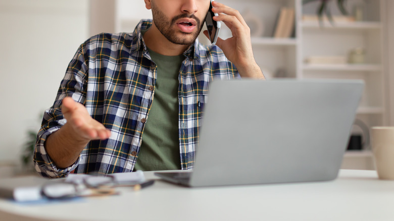 man using phone and laptop