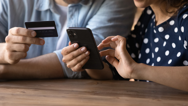 Couple using phone and card