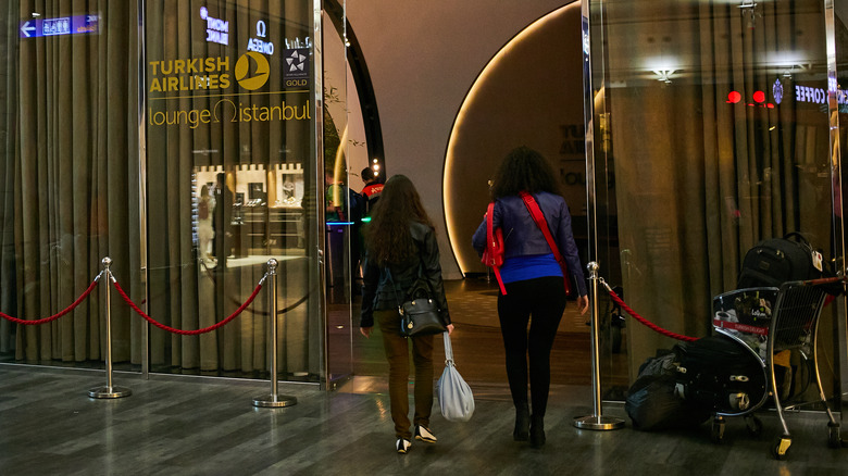 Two women walking into an airport lounge.