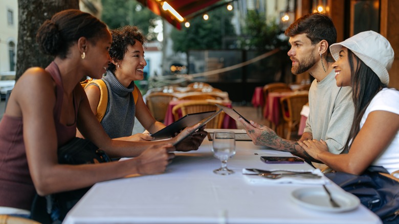 A group of smiling tourists discussing what to order at a restaurant