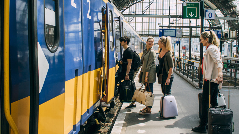 People boarding train at station with luggage in hand