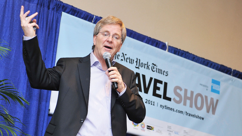 Rick Steves on stage in suit with microphone