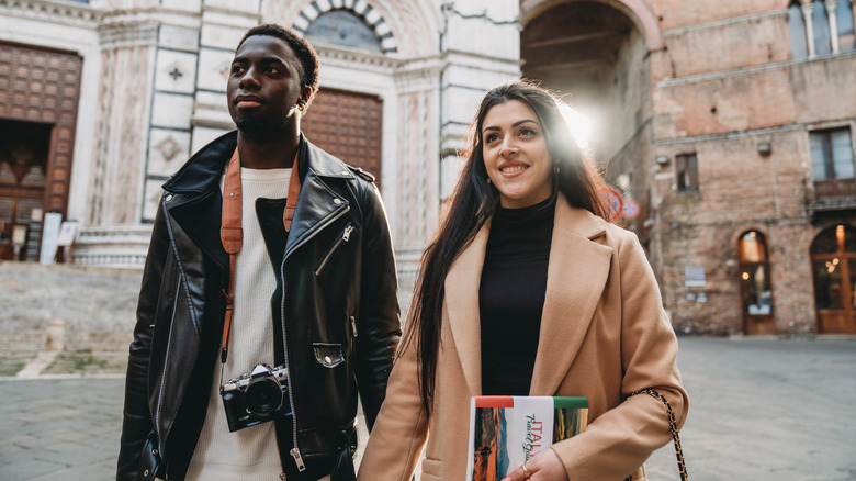 Couple walking around Italy with a guidebook