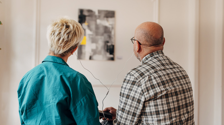 Couple sharing headphones in an art gallery