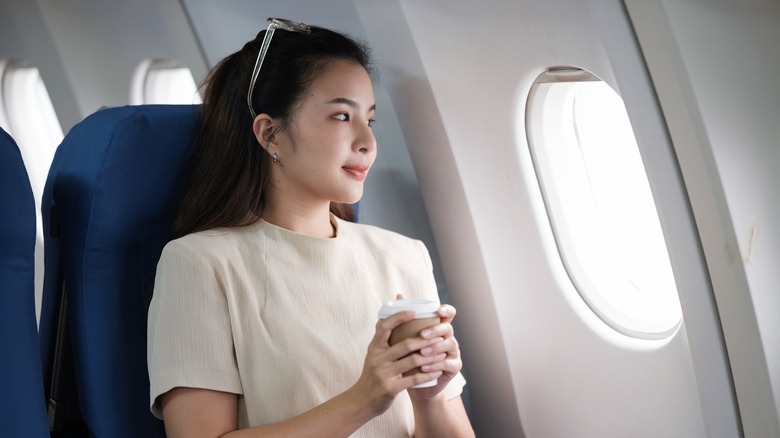 Woman holding coffee on plane