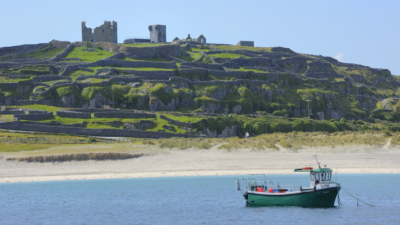 Castle ruins, walls, beaches of Aran Islands with a fishing boat in Ireland