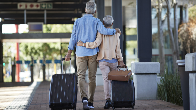 A romantic older couple with rolling suitcases