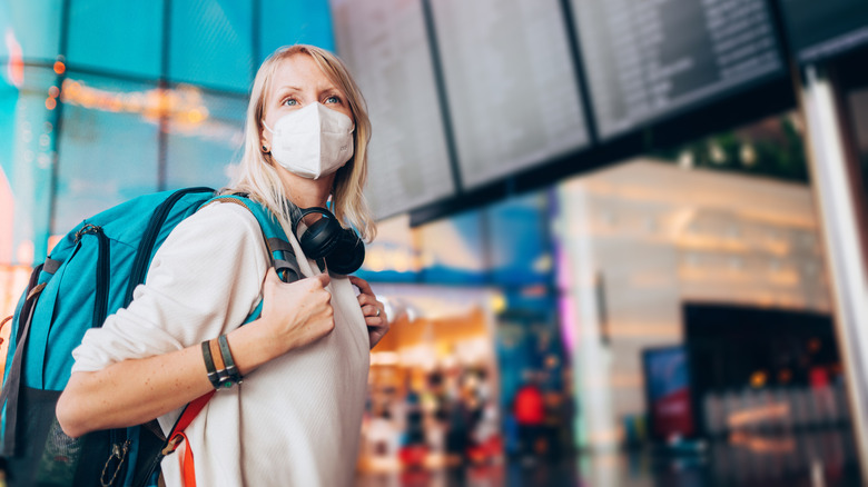 Woman with backpack and a face covering traveling at an airport