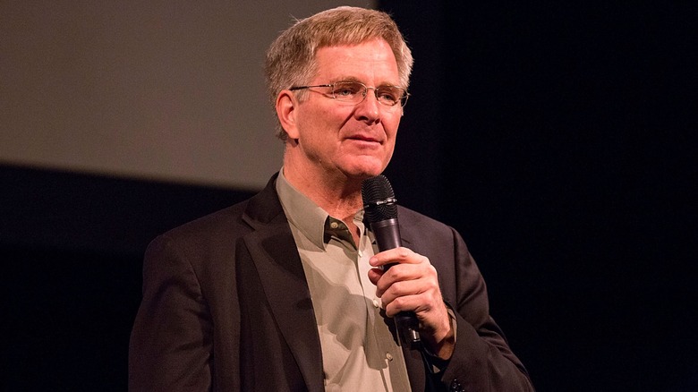 Rick Steves holding a microphone and speaking at event