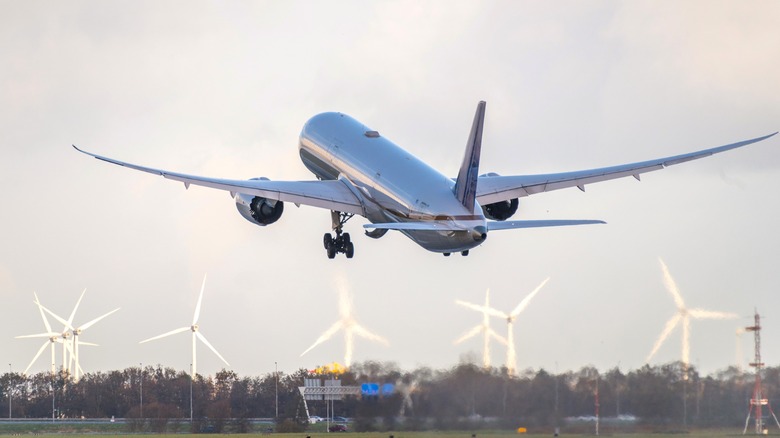 Plane taking off, wind turbines in background