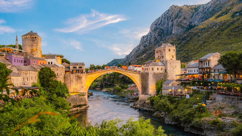 Stone bridge over river with a mountain backdrop in Bosnia