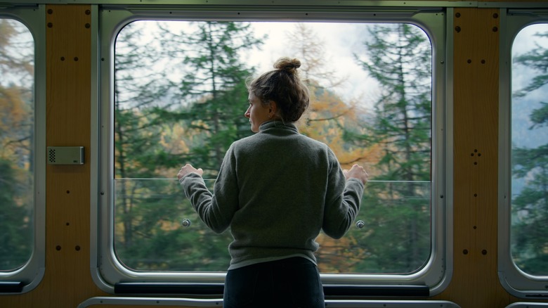 standing woman looking out of a train window