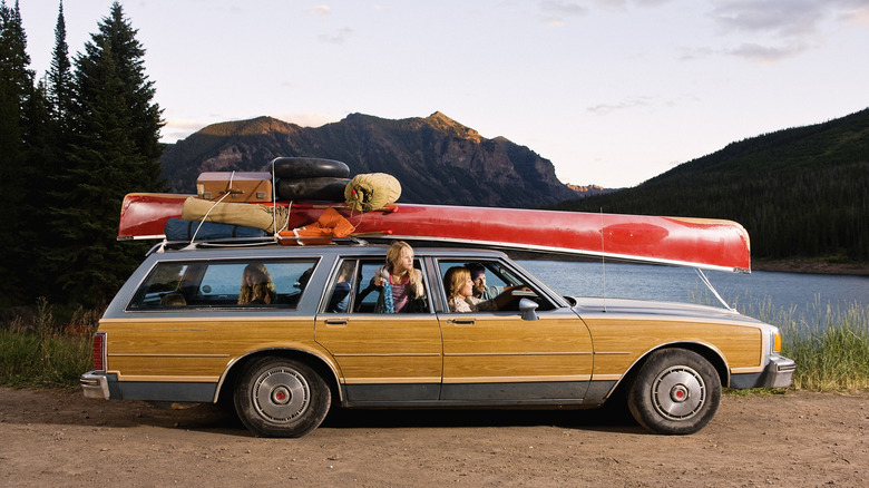 Family in a car with a canoe and luggage on top