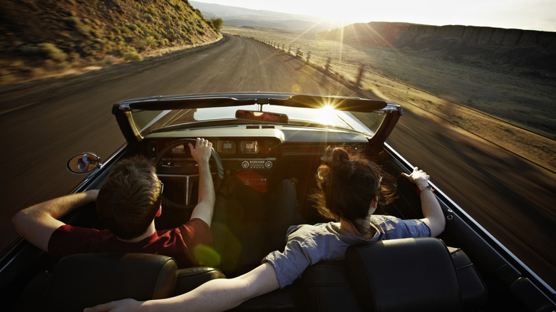 Two people in a convertible during a road trip