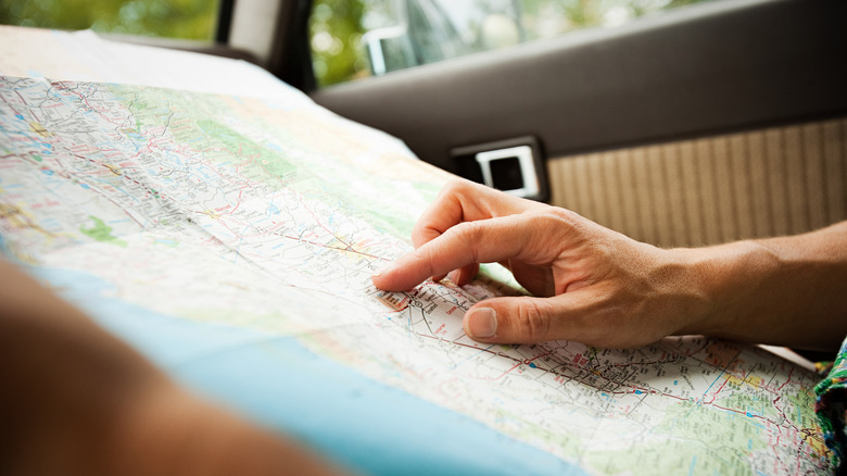 Hand pointing on a paper map in a car