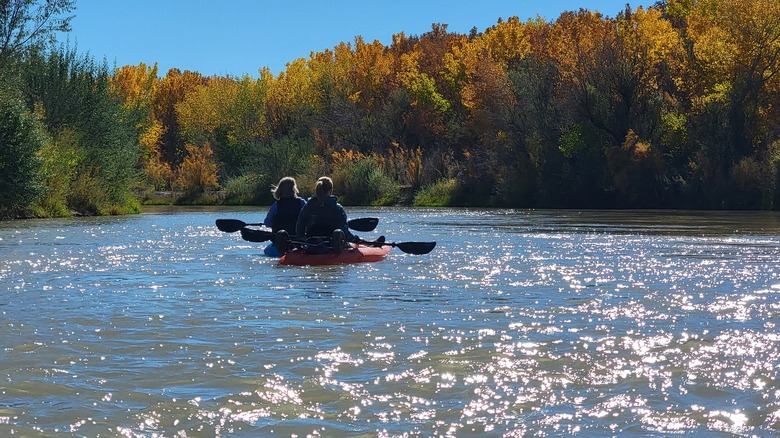 Two women kayaking along the beautiful Rio Grande river while it's calm and the sky is clear