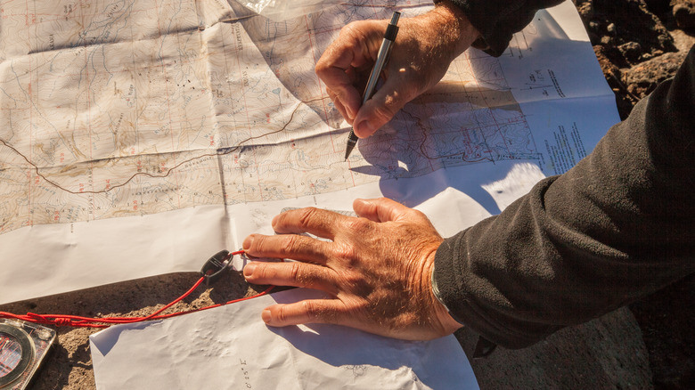 hands marking topographical map