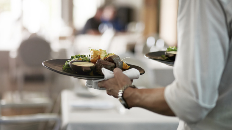 Food at a high-end restaurant being delivered by a waiter