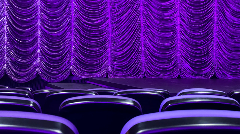 Empty seats and a drawn curtain on a purple stage