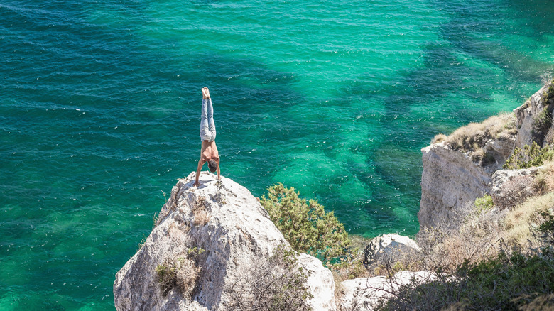 Man doing a handstand on a cliff in Cagliari, Sardinia, Italy