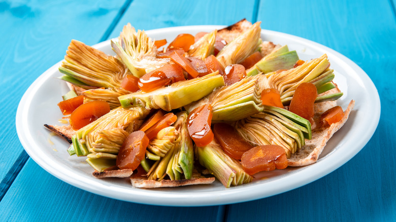 Italian bottarga dish with artichokes on a blue table