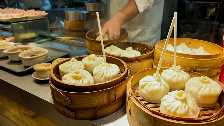 Chinese dim sum in steamers on counter with chefs in background