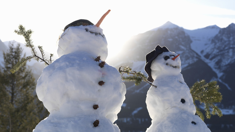 Two snowmen in front of the mountains