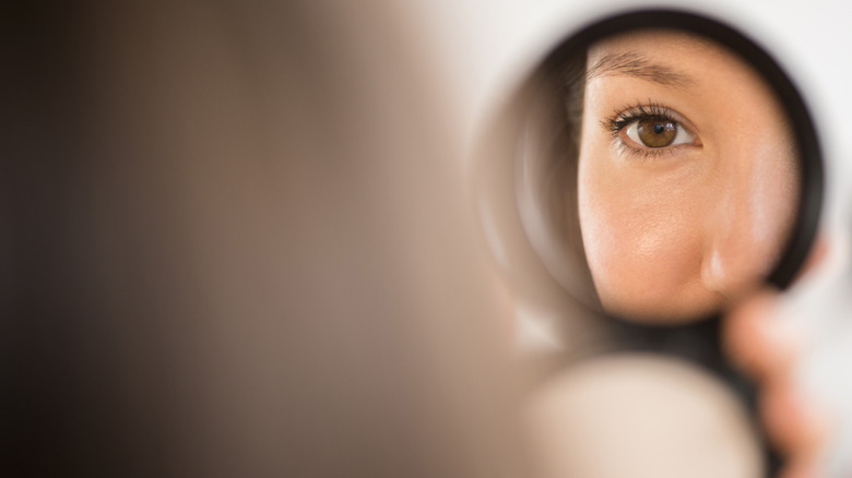 A woman looking into a compact mirror.