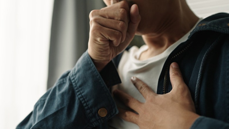 A close up of a man coughing.