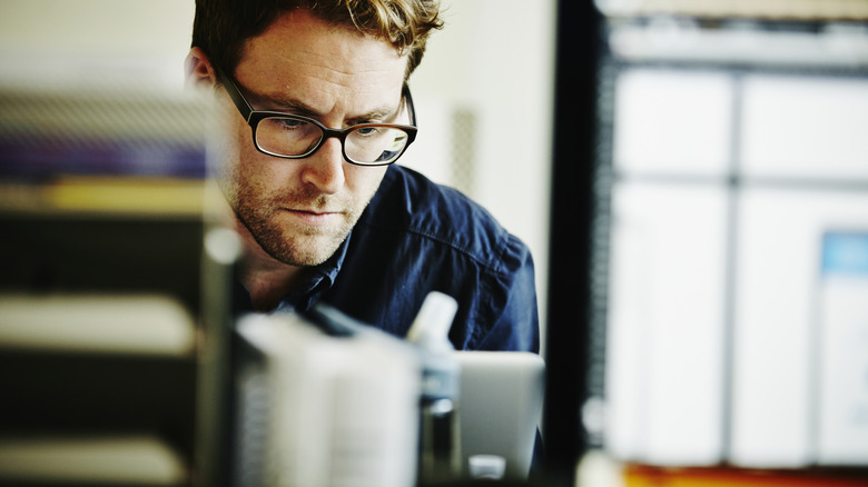 A man wearing glasses and looking down.