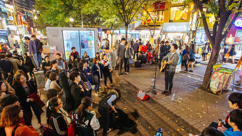 A crowd watches a street musician in Hongdae