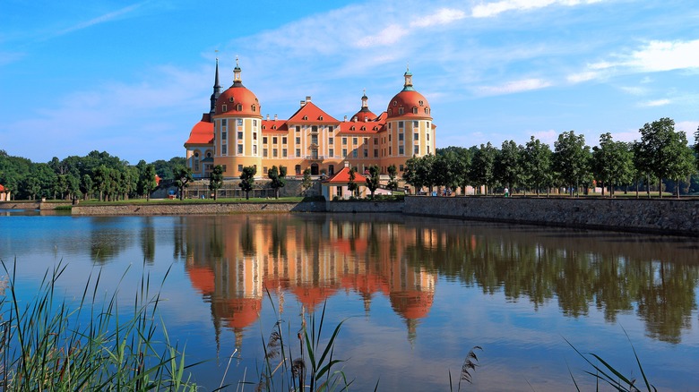 The orange facade of Moritzburg Castle reflecting in the lake below it in Saxony, Germany