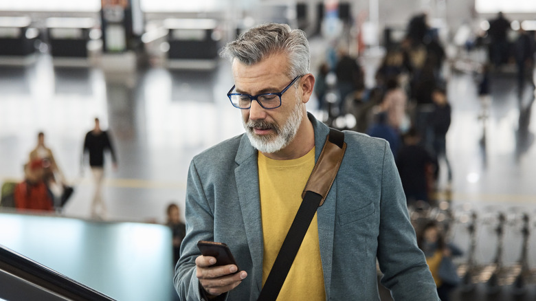 Man looking at phone in airport