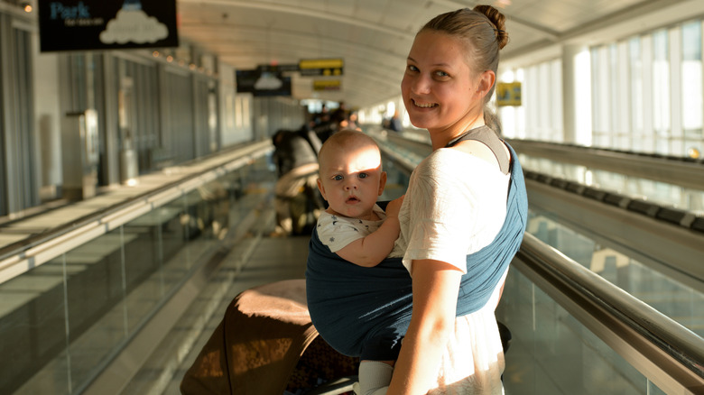 A smiling woman with a baby in a sling