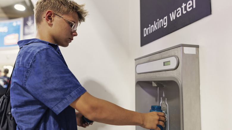 Teen refilling water bottle